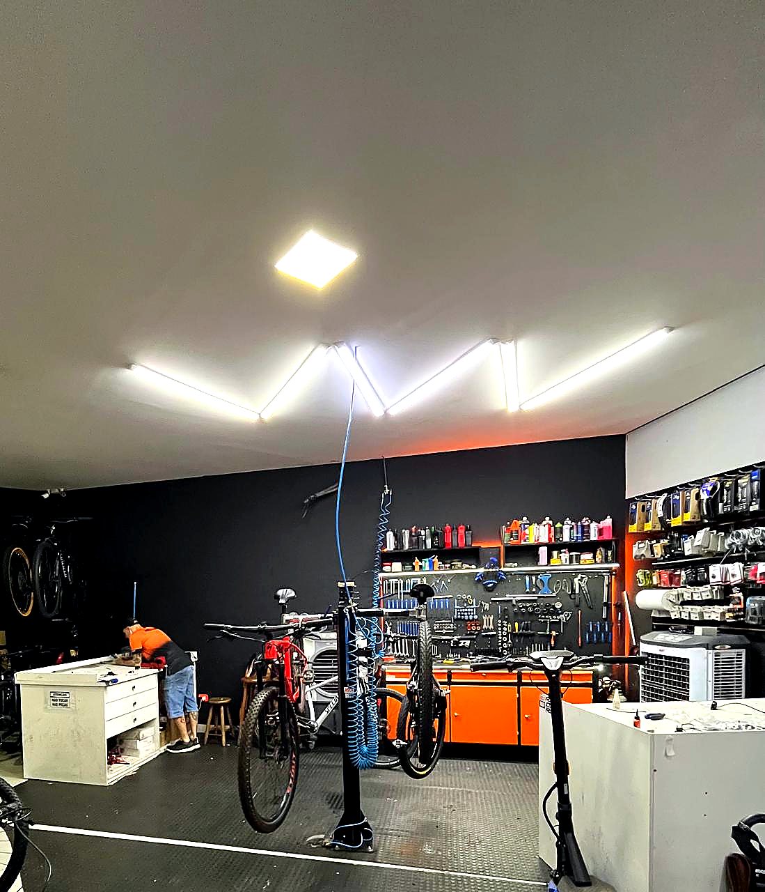 Oficina especializada da Nei Bike Center com bancada de ferramentas, bikes em manutenção e iluminação técnica